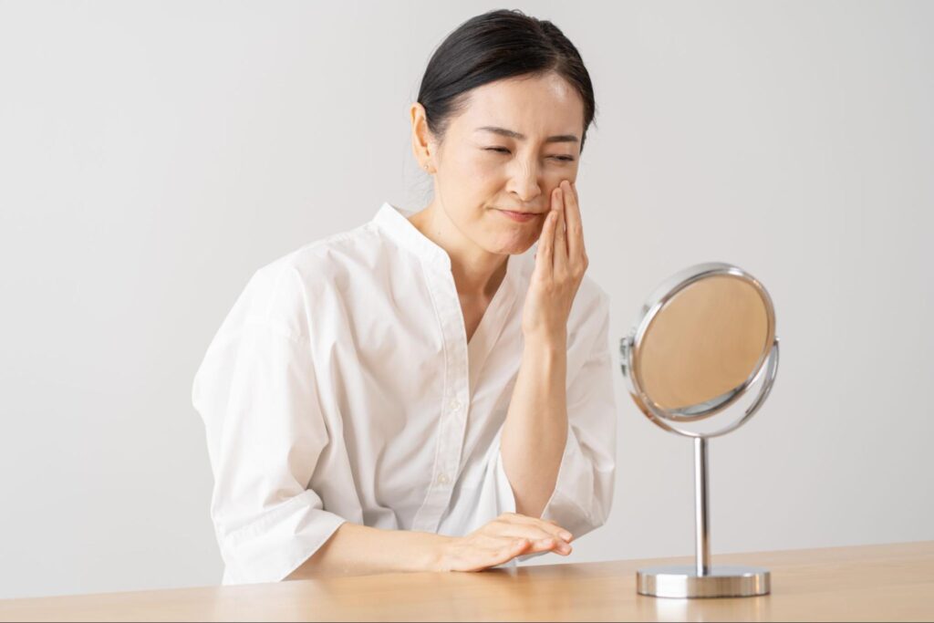 鏡を見てたるみを気にしている女性
