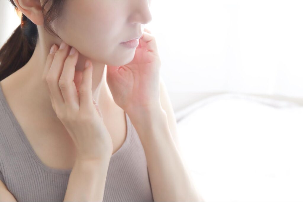 フェイスラインに手を当てている女性