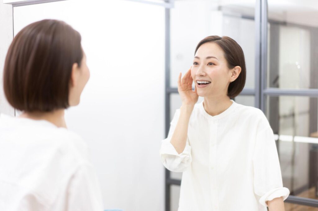 鏡で口元のシワをチェックする女性