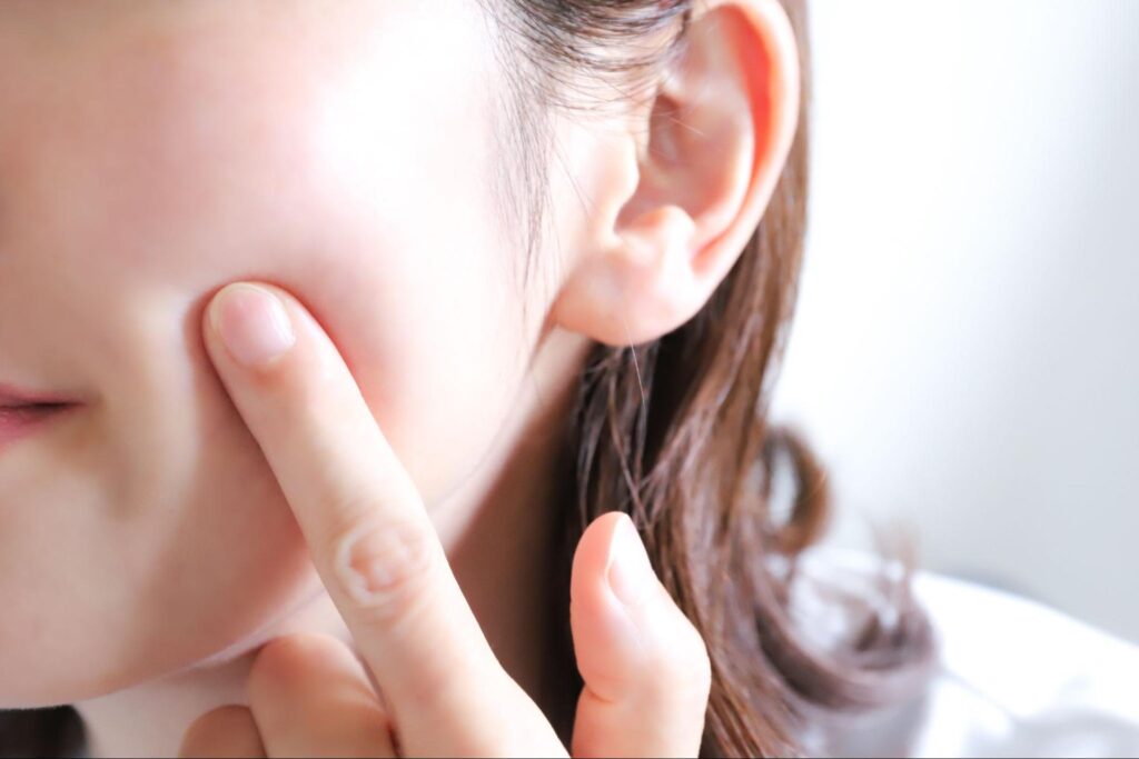 頬に指を当てている女性