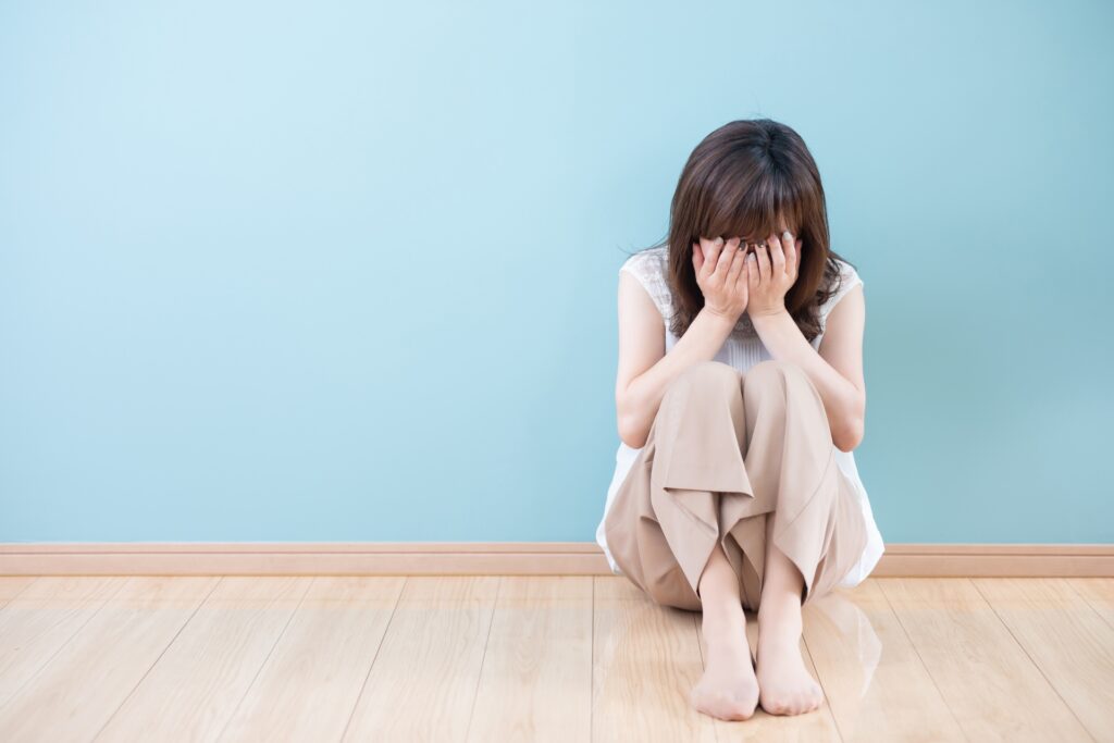 うずくまって顔を覆う女性