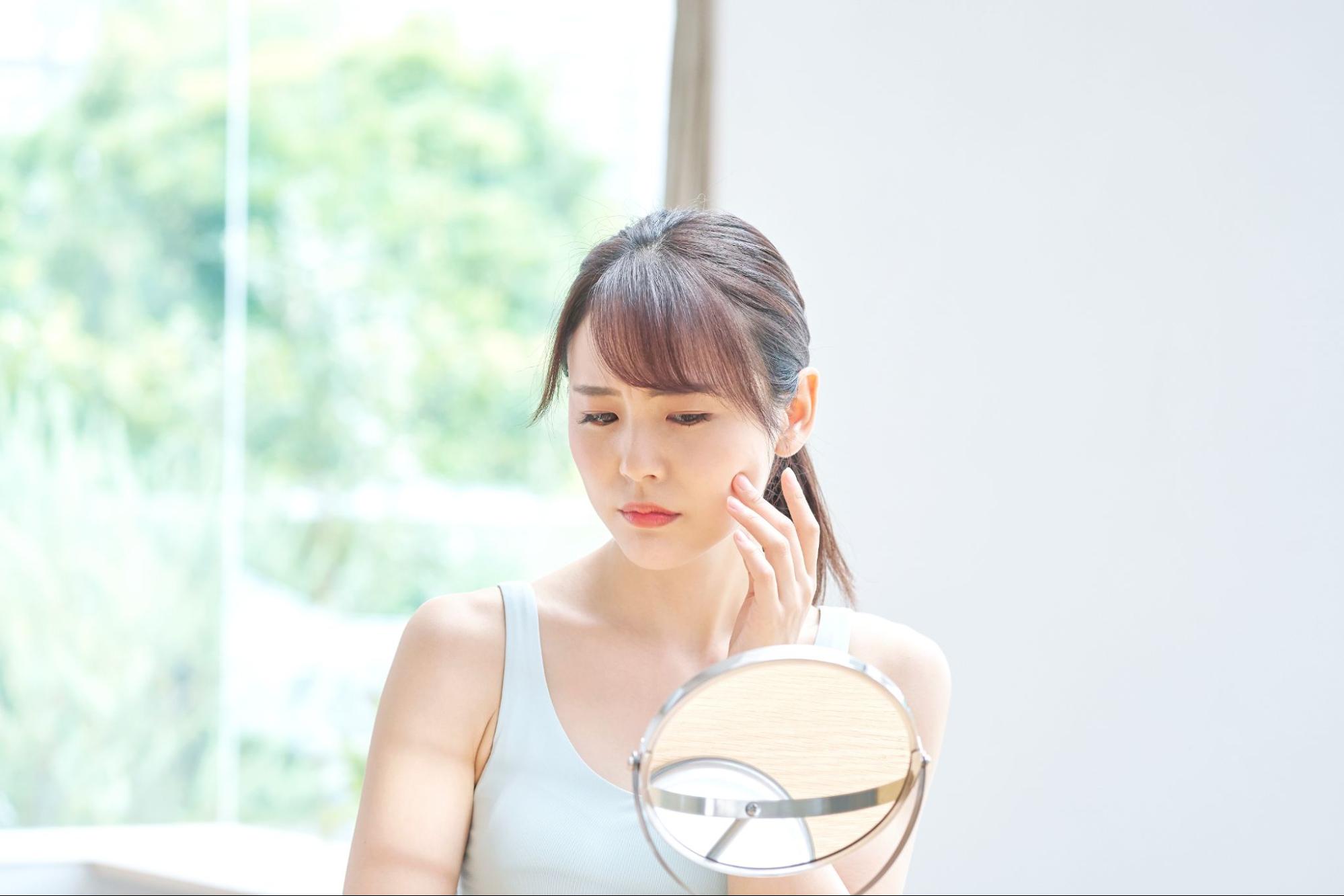 鏡を見てたるみを気にしている女性