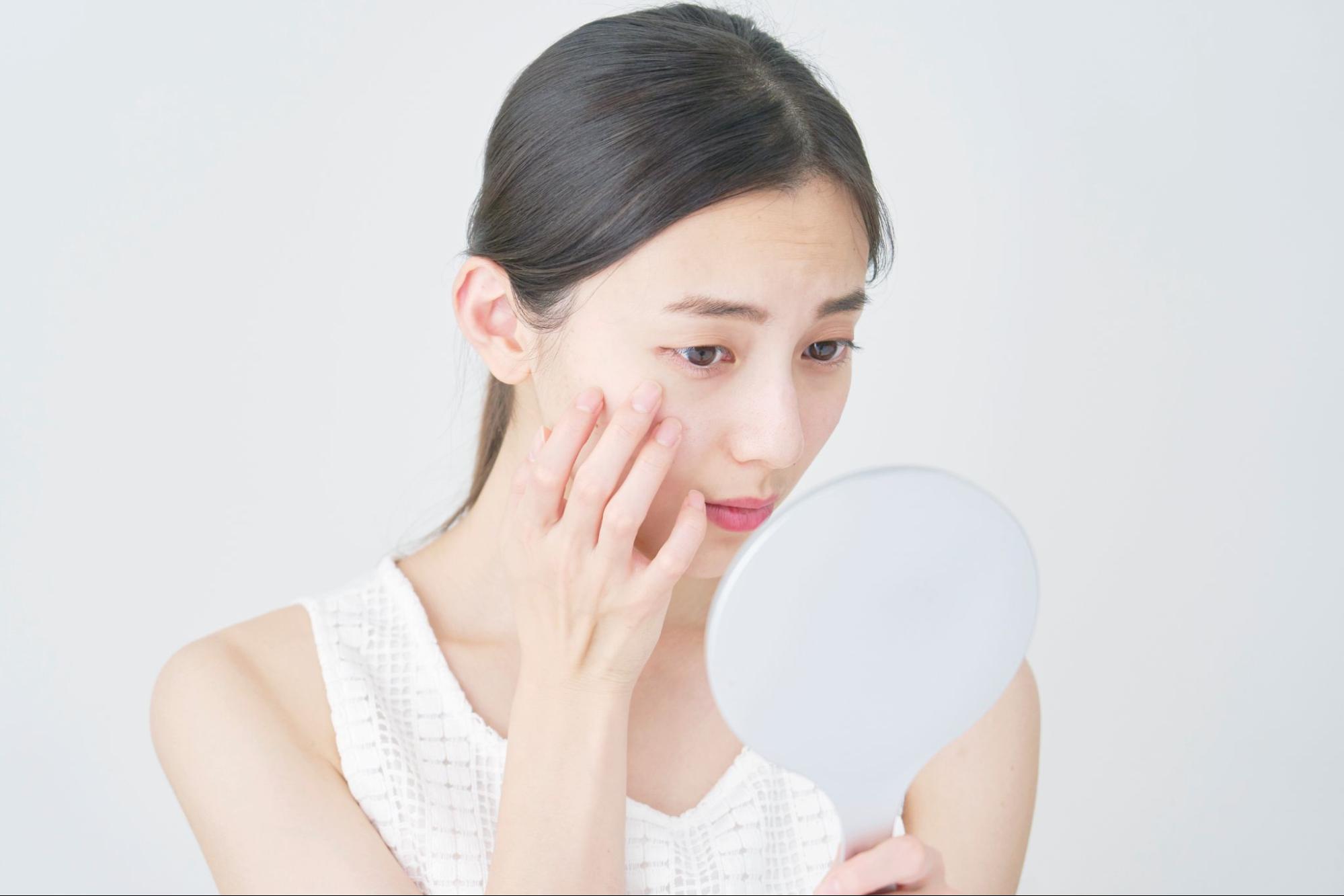 鏡で二重幅をチェックしている女性