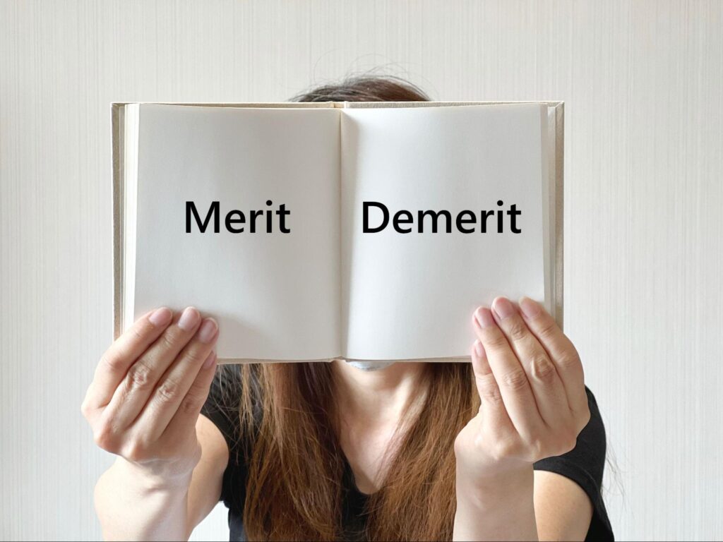 メリットデメリットと書かれたノートを持つ女性