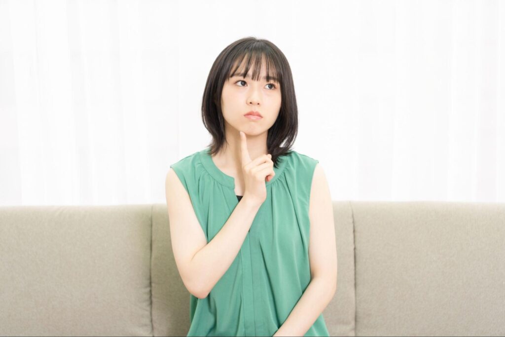 人差し指を顎に当てて何かを考えている女性