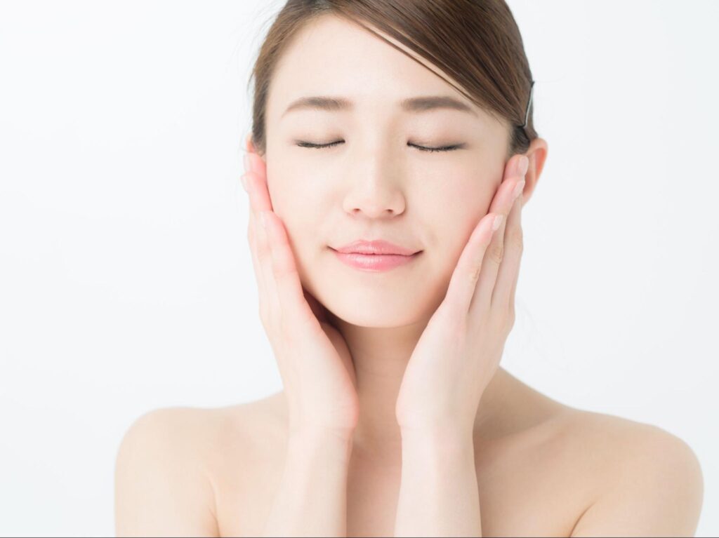両頬に手を添える美肌の女性