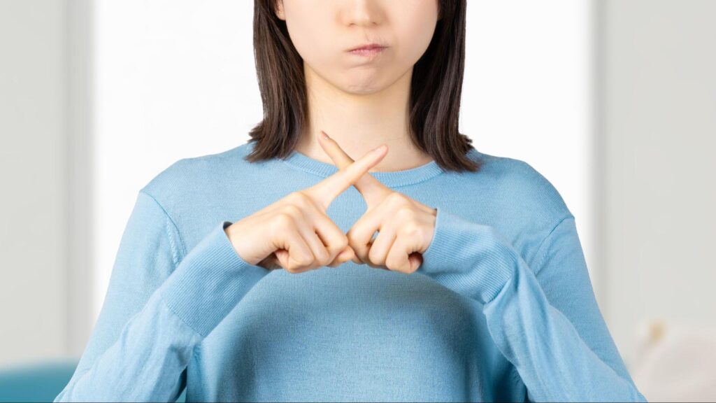 指でバツを作る女性