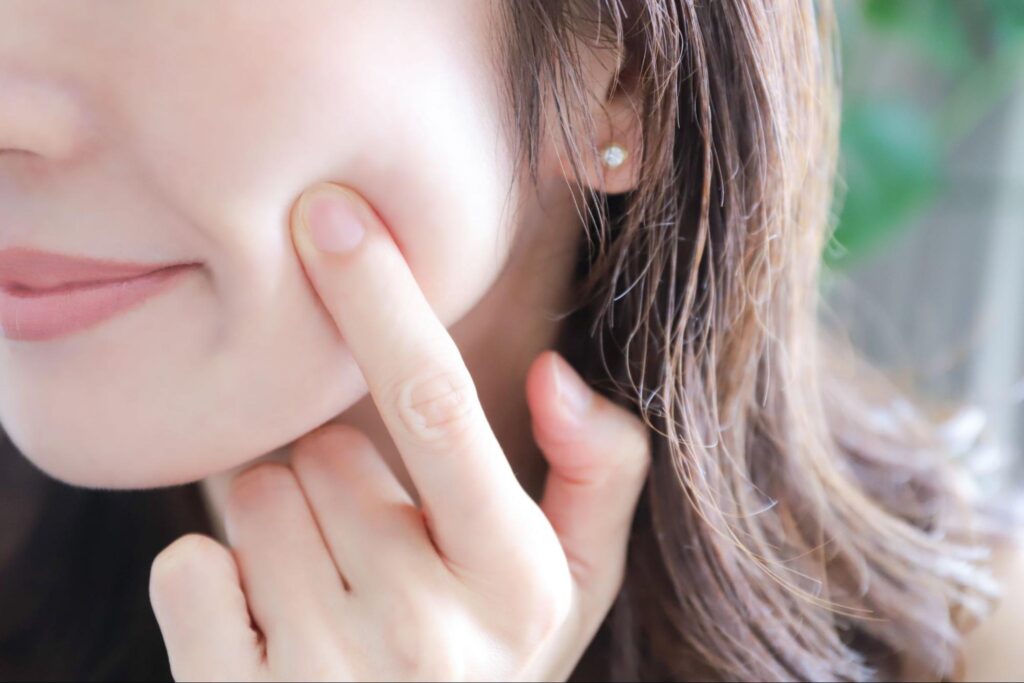 頬に人差し指を当てる女性
