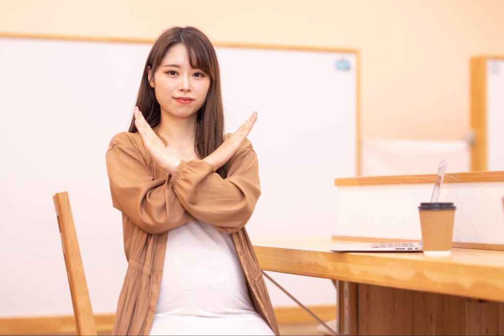 手でバツを作る女性